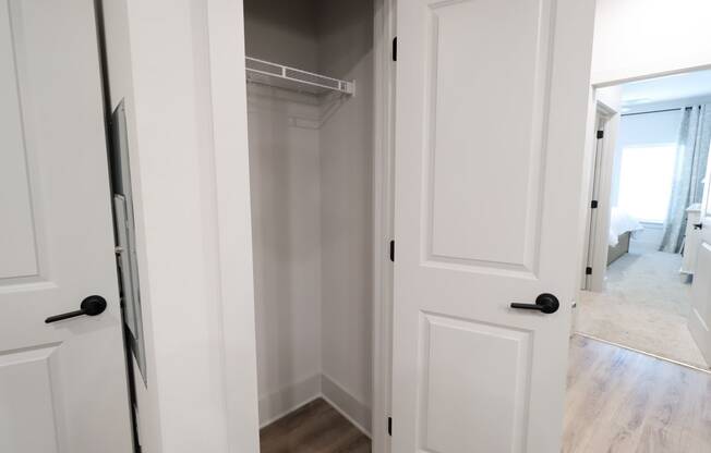 a walk in closet with white doors and a white closet door open to a bedroom