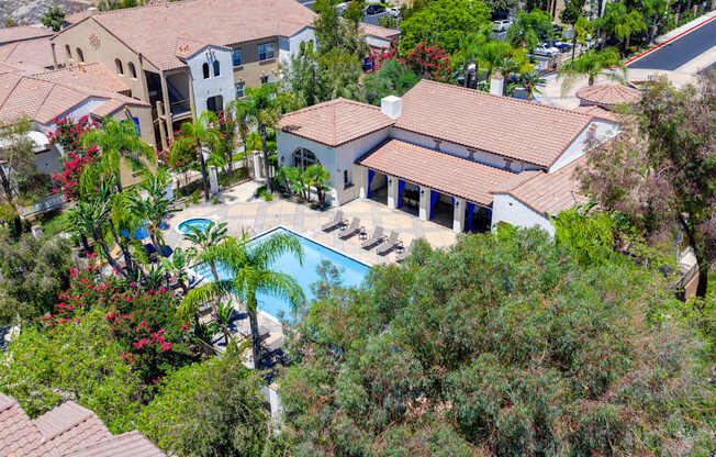 A bird's eye view of a house with a pool surrounded by trees.