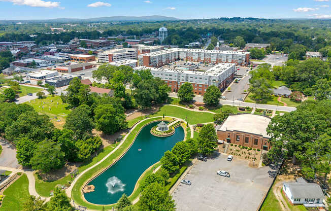 A large building complex with a fountain in the middle of a green area.