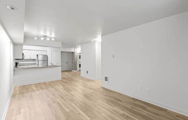 A spacious room with wooden flooring and white walls.