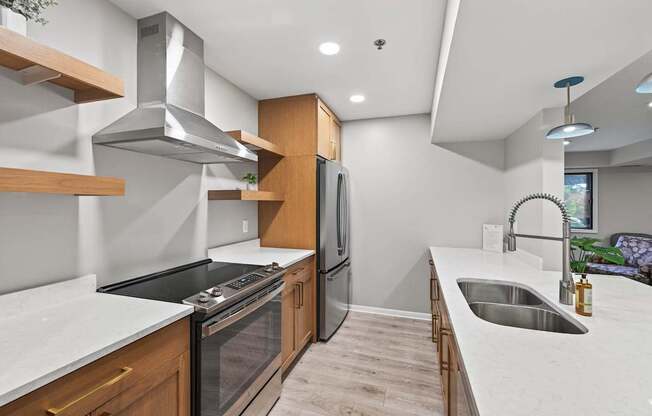 A modern kitchen with a stainless steel range hood and a double sink.