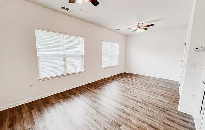 an empty living room with wood floors and a ceiling fan