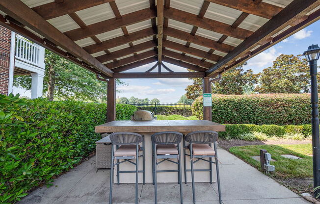 a pergola with a table and chairs on a concrete patio