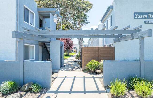 A white house with a wooden pergola in front.