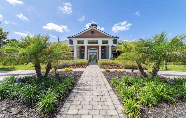 a house with a pathway and palm trees in front of it
