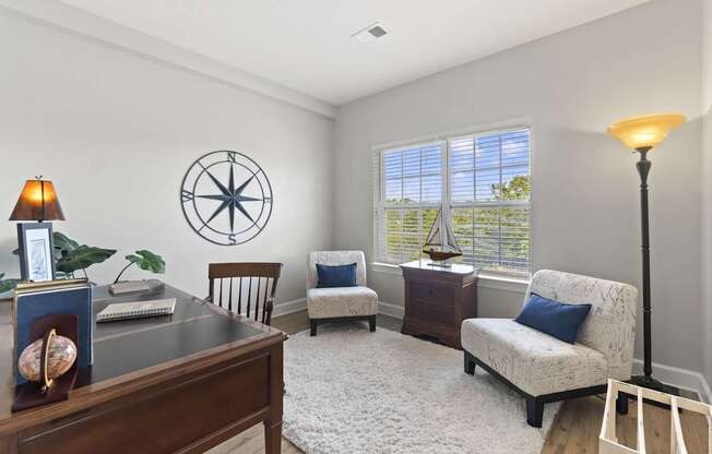 A room with a compass on the wall and a lamp on the desk.