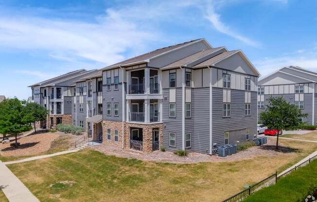 A large apartment complex with multiple buildings and a green lawn in front.
