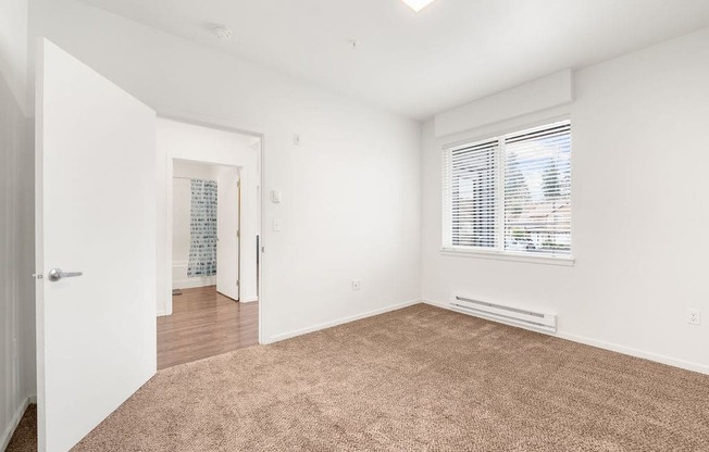 a bedroom with a large window and white walls