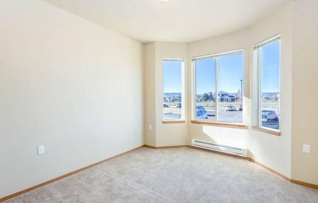 an empty room with three windows and a view of a parking lot