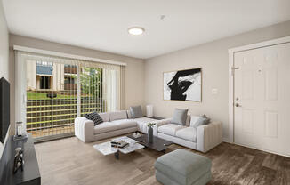 Model living room with a white couch and a coffee table in front of a large window with