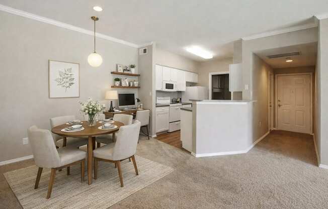 A dining room with a table set for two and a kitchen area in the background.