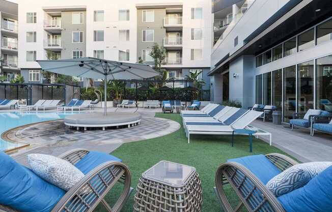 A round pool surrounded by lounge chairs and umbrellas.