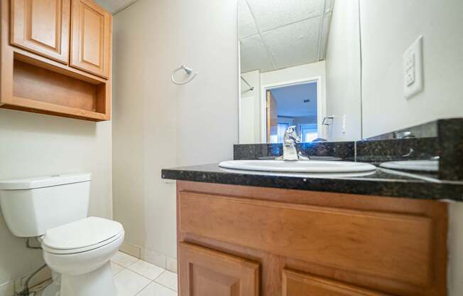 A bathroom with a toilet, sink, and wooden cabinet.