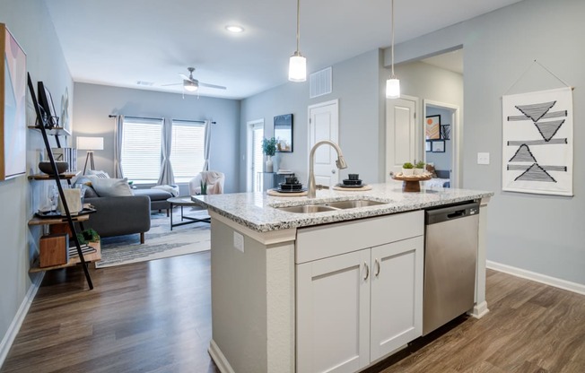 a kitchen with an island and a sink in front of a living room with a couch
