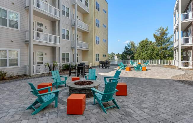 an outdoor patio with chairs and a fire pit in front of an apartment building