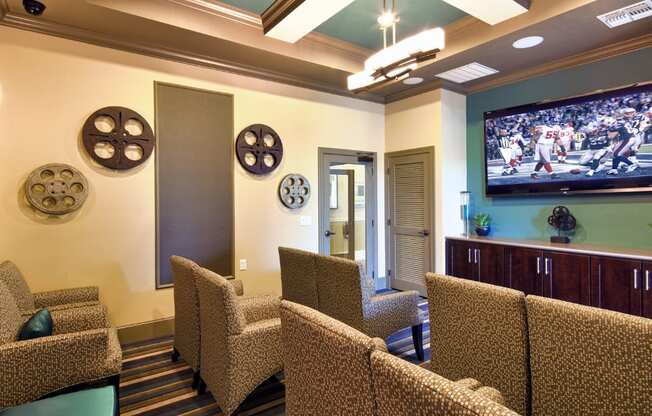A room with a row of chairs and a television playing a football game.