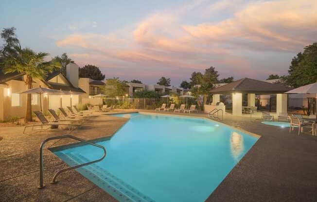 a swimming pool with chairs and umbrellas in front of a resort pool