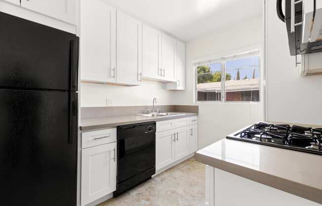 a kitchen with white cabinets and a black refrigerator