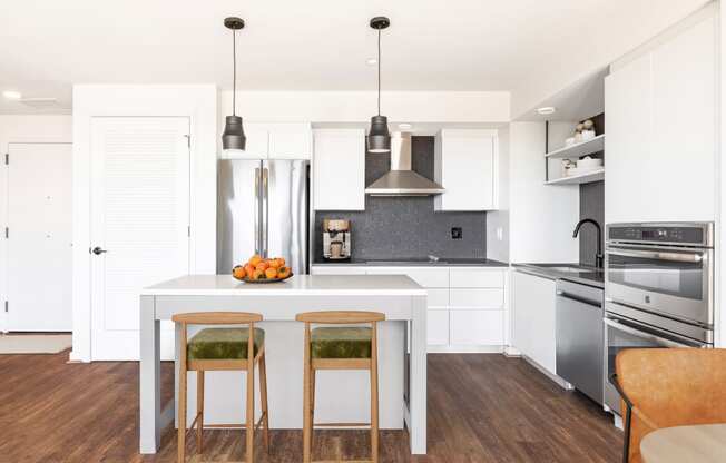 a kitchen with white cabinets and a white island with three stools