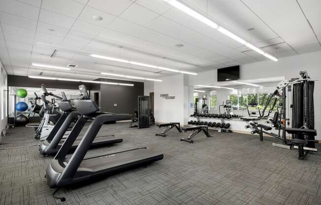 a gym with cardio equipment and weights in a building with white ceilings