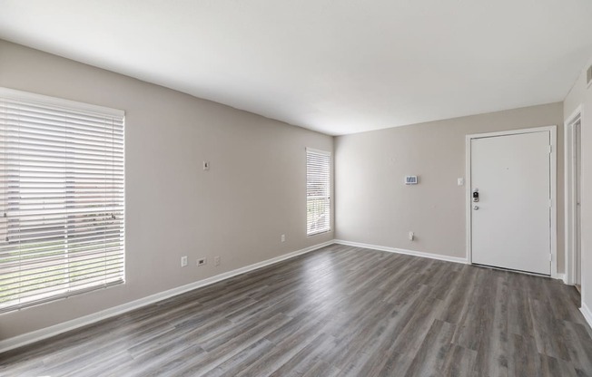 an empty living room with wood floors and a white door