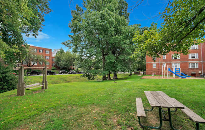 A park with a picnic table and a playground in the background.