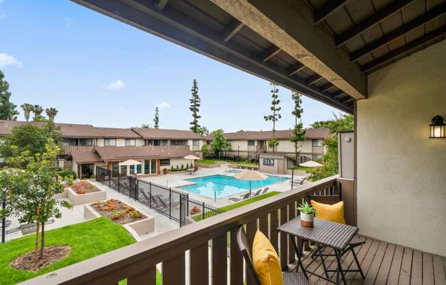 a balcony with a table and chairs and a swimming pool in the background