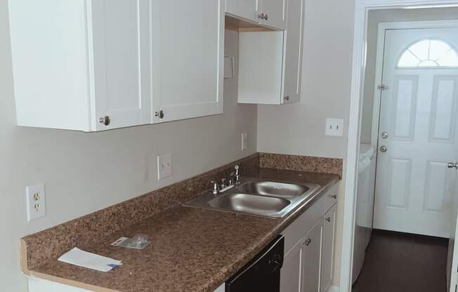 a kitchen with white cabinets and a black dishwasher