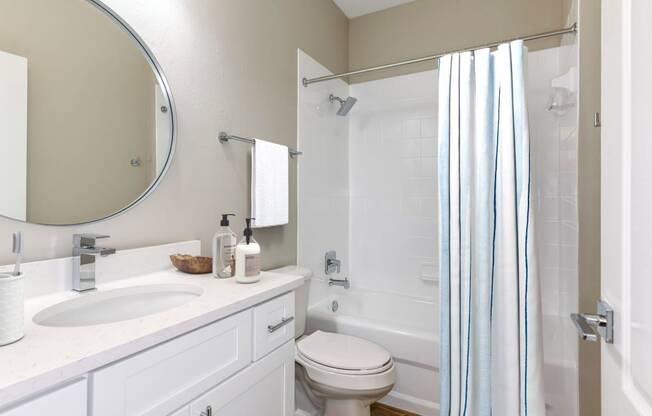 a bathroom with a white sink and toilet next to a white bathtub with a shower curtain