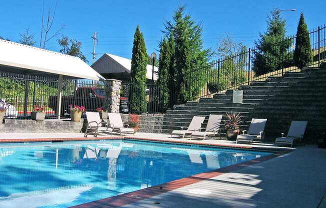 A pool with a red and blue border and white lounge chairs.