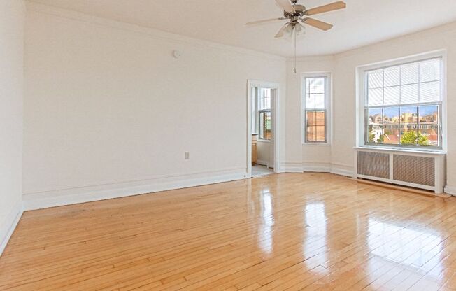 an empty living room with hardwood floors and a ceiling fan at the calverton apartment building in washington dc