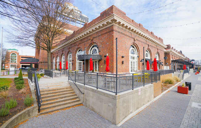 A red brick building with a black fence and stairs leading up to it.