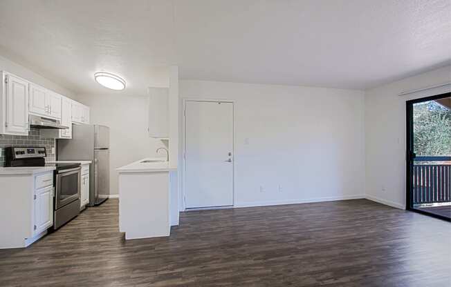 an empty kitchen with white cabinets and stainless steel appliances and a sliding glass door