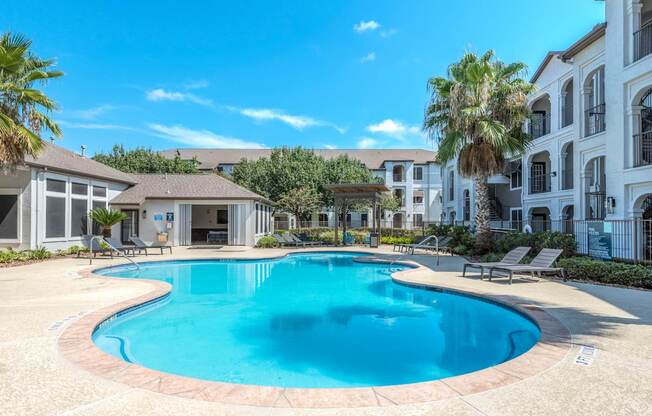 A large swimming pool in a residential area surrounded by palm trees.