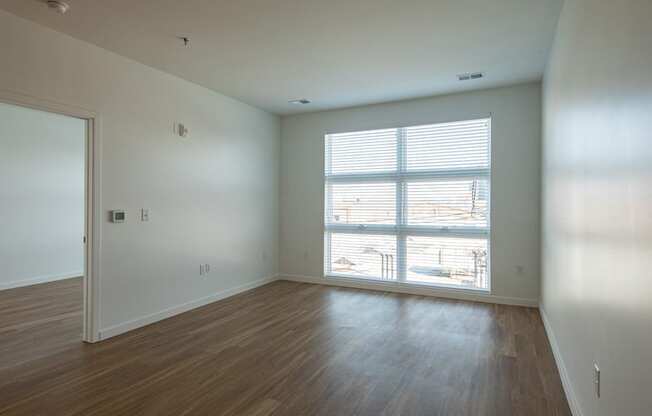 an empty living room with wood floors and a large window