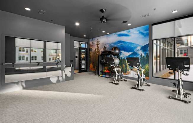A modern gym with a large mirror and exercise bikes.