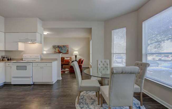 A modern kitchen with white cabinets and a dining area with a glass table.