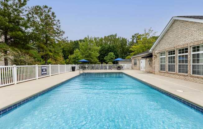A long rectangular pool with a white fence around it.