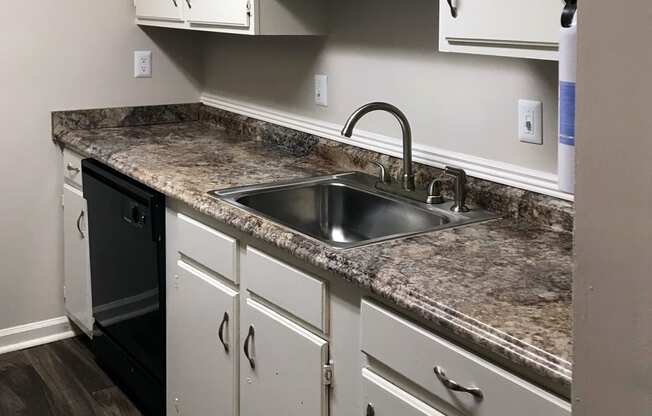 stainless steel sink in granite style countertop with ample cabinetry