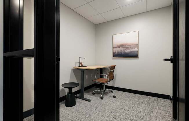 A room with a desk, chair, and a painting on the wall.