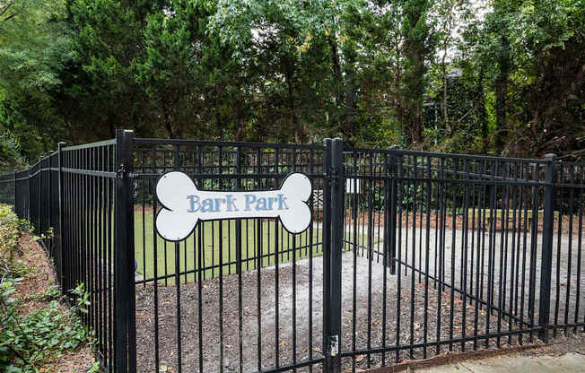 A black fence with a sign that says Bark Park.