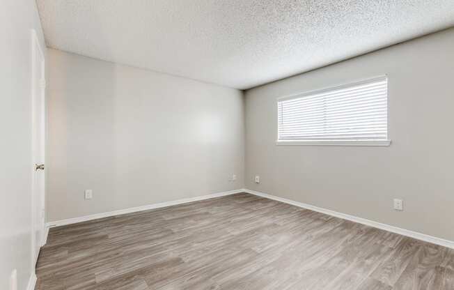 the spacious living room with wood flooring and a window