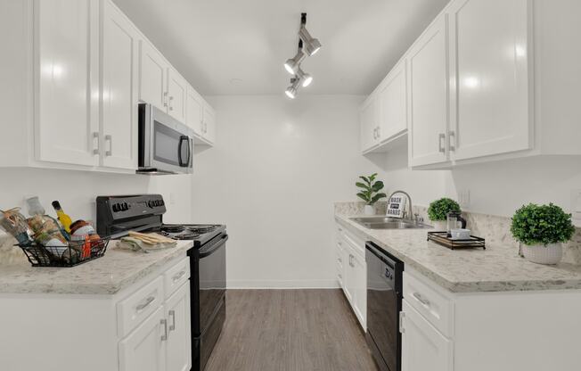 a kitchen with white cabinets and white counter tops and black appliances