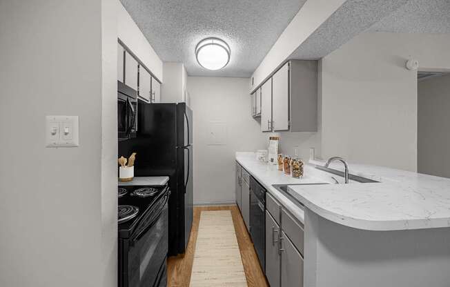 A kitchen with a black refrigerator and a white counter top.