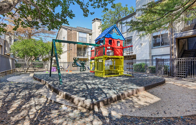 A playground with a red and yellow slide and a blue and yellow playhouse.