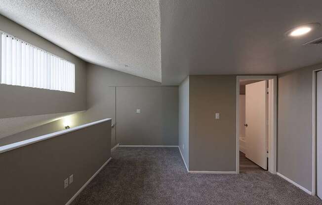 an empty living room with a door to a hallway and a window