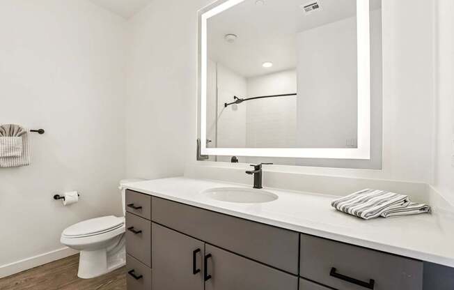 A bathroom with a white counter top and a white toilet.