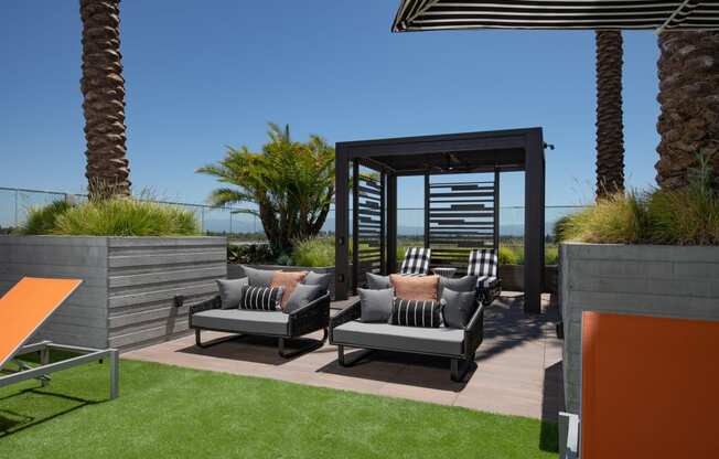 a patio with lounge chairs and a pergola with palm trees in the background