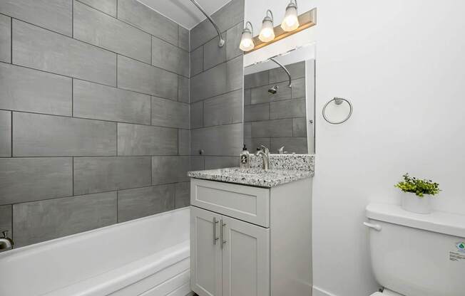 A bathroom with a white tub, sink, and toilet at Gainsborough Court Apartments, Fairfax, VA