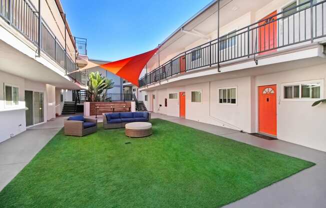 the courtyard of a building with a lawn and a red door